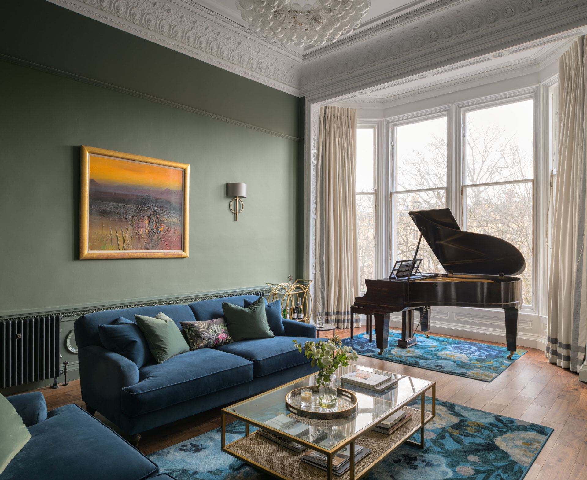 Green-walled Edinburgh drawing room with ornate cornicing, blue velvet sofas and a grand piano in the bay window